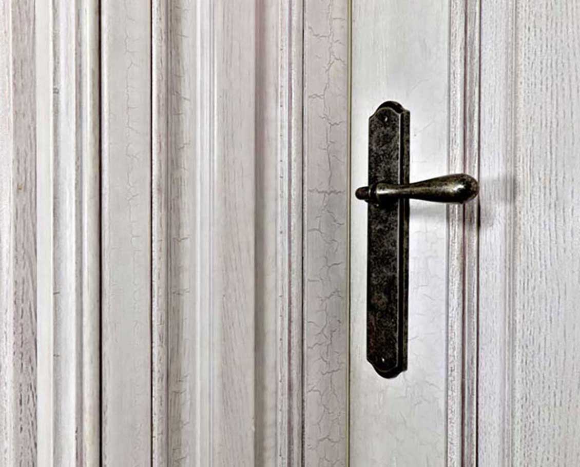 Detal - białe drzwi drewniane - część środkowa z ciemną metalową klamką.