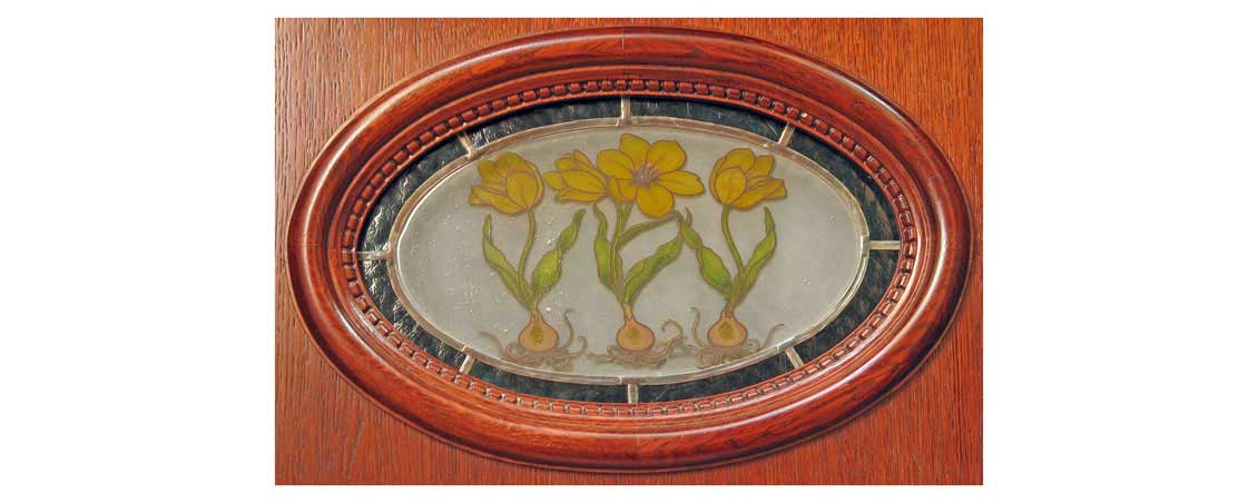 Owalna szybka w drewnianych drzwiach zewnętrznych z namalowanymi na niej pięknymi żółtymi kwiatami.