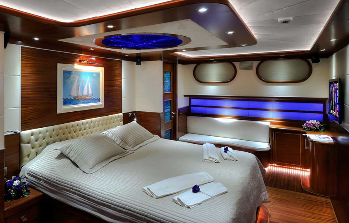 Piękne drewniane meble na jacht. Luksusowa kabina w większości wyłożona drewnem i urządzona na wysoki połysk. Na pierwszym planie luksusowe łóżko na wymiar.