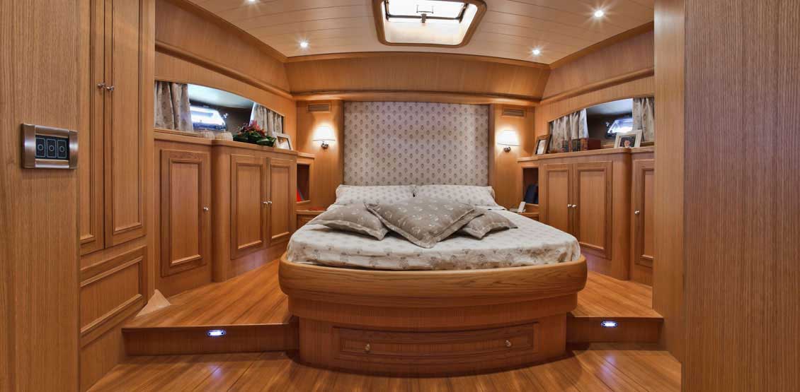 Drewniane meble do zabudowy w luksusowej kajucie właściwie w całości wyłożonej drewnem. W centralnym miejscu eleganckie drewniane łóżko na wymiar.