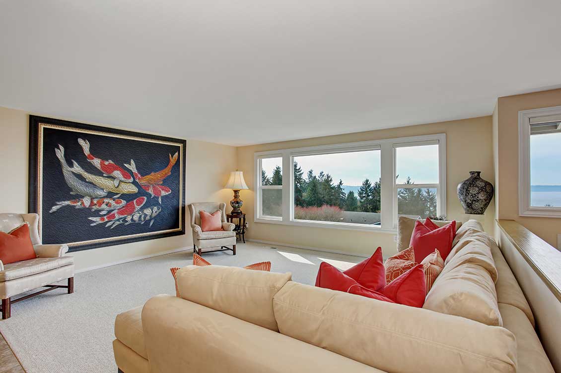 Nowoczesne meble do apartamentów - ekskluzywne meble białe i kremowe: wygodne kanapa / sofa i fotele. Na ścianie duży obraz przedstawiający kolorowe ryby.