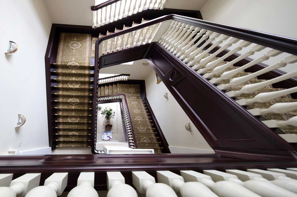 Luksusowe drewniane schody na wymiar ciągnące się przez kilka pięter - schody kręte, widok z góry.